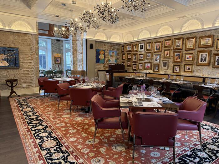 Dining room with gallery wall of framed portraits and chandeliers