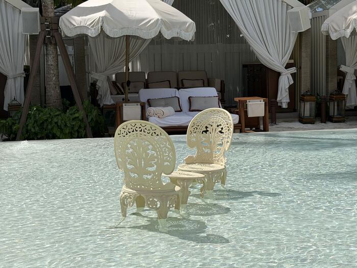 Ornate poolside chairs set in shallow water